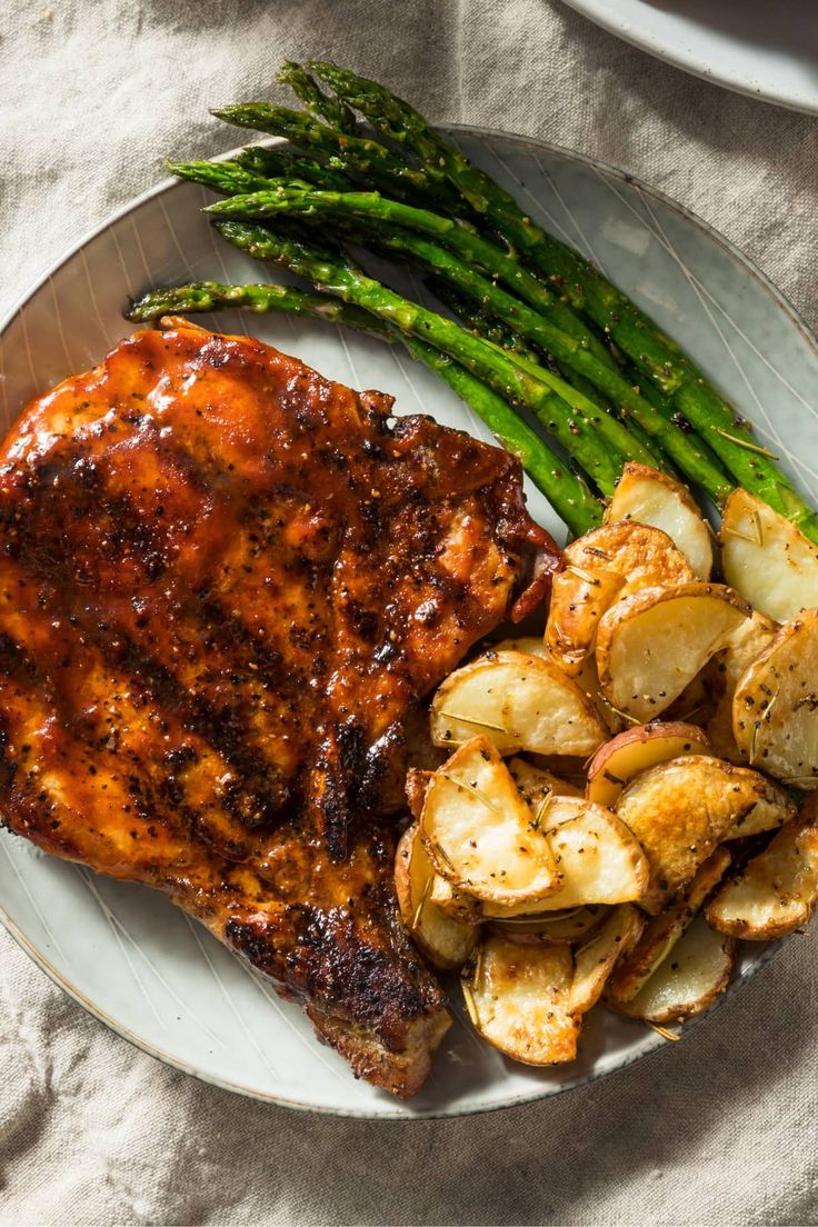 a plate with meat, potatoes and asparagus on it