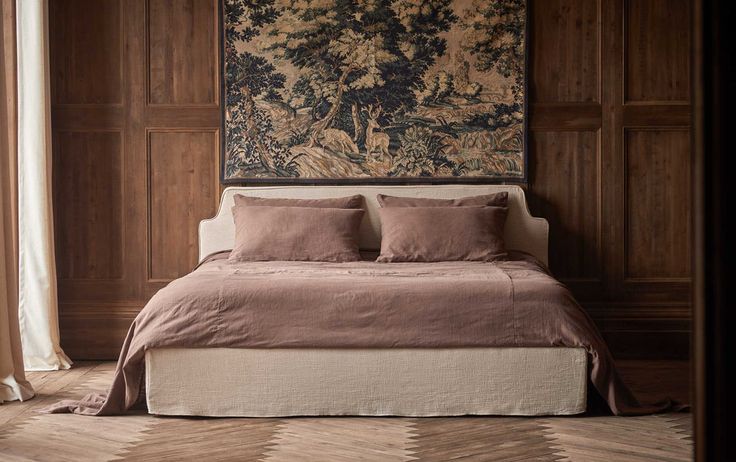 a bed with two pillows on top of it in front of a wall hanging tapestry