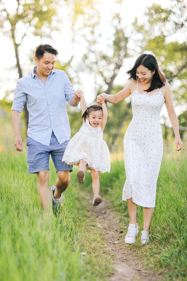 a man and woman holding hands as they walk down a path with a baby in the air