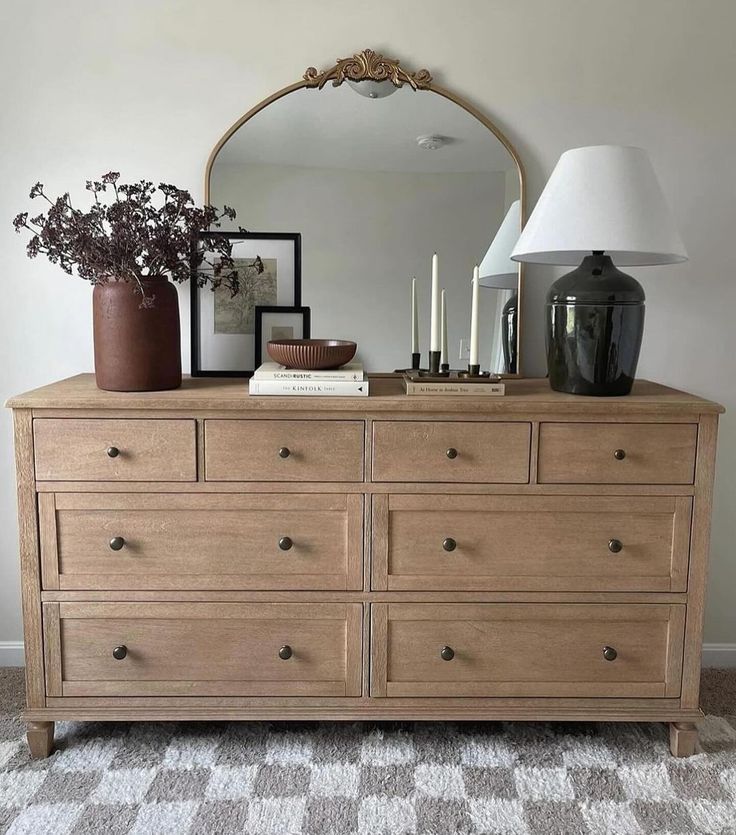 a dresser with a mirror, vases and candles on it in a living room