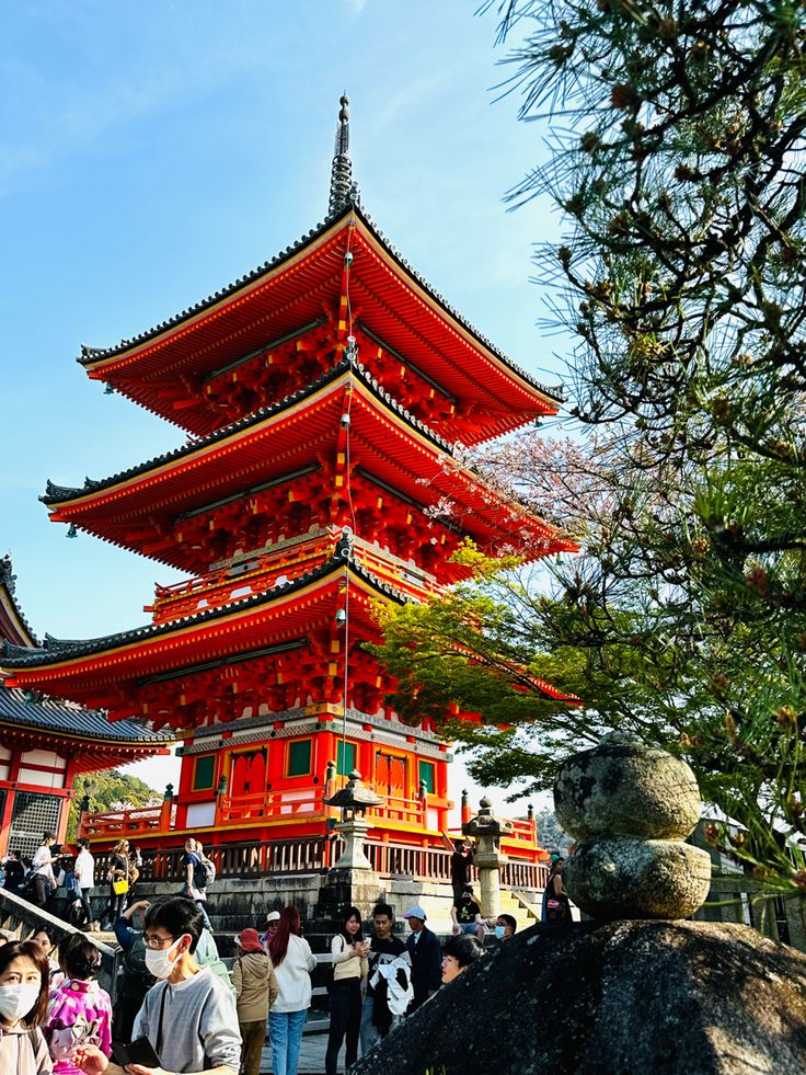 people are standing in front of a tall red pagoda