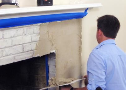 a man standing in front of a fire place next to a white fireplace with blue tape on it