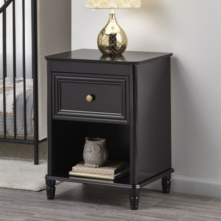 a night stand with an open drawer on the bottom and a gold vase on top