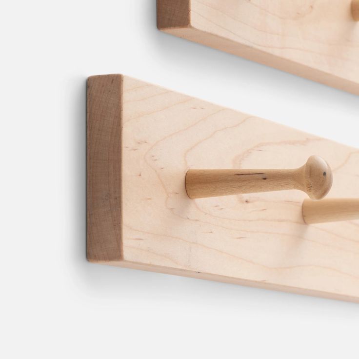 two wooden pegs hang on the wall next to each other