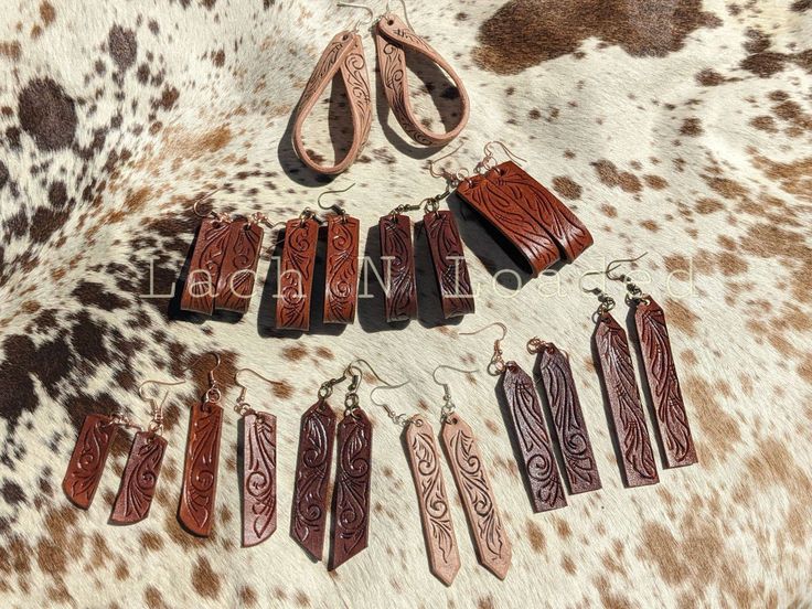 "Handmade tooled leather earrings done in a freehand carved filigree design. Small dangles measure 1.5\" long to the big twisted loops at 3\". Assorted leather colors in natural, acorn and fudge brown with antique brass, silver  and copper hardware. Earrings will come boxed and what you see is what you get! Feel free to message me with any questions." Hand Tooled Brown Dangle Earrings, Brown Hand Tooled Dangle Earrings, Rustic Hand Tooled Leather Earrings, Rustic Brown Hand-tooled Earrings, Rustic Brown Hand Tooled Earrings, Artisan Handcrafted Brown Jewelry, Rustic Brown Engraved Jewelry, Brown Leather Engraved Jewelry, Artisan Brown Etched Jewelry