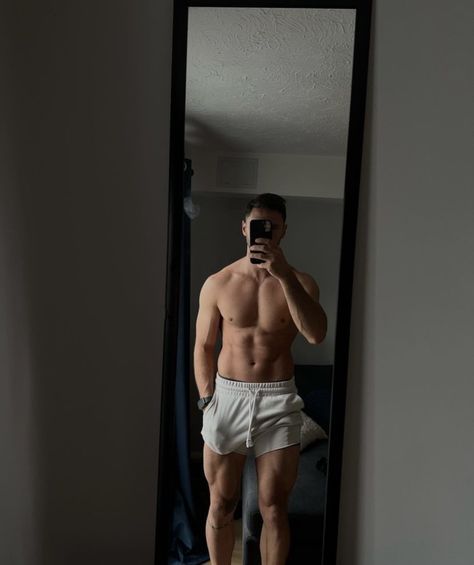 a shirtless man taking a selfie in front of a mirror