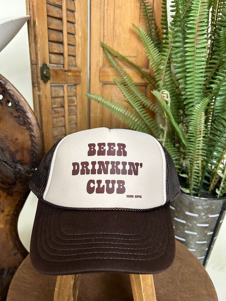 Accessorize your summer look with this stylish Beer Drinkin' Club Trucker Hat! This brown and tan trucker cap features a classic graphic in a brown retro font. Vintage Summer Baseball Cap For Outdoor, Vintage Trucker Hat With Letter Print And Curved Brim, Retro Summer Trucker Hat For Outdoor, Retro Brown Trucker Hat With Letter Print, Vintage Summer Trucker Hat For Outdoor Activities, Vintage Trucker Hat With Letter Print, Retro Summer Snapback Hat With Letter Print, Retro Snapback Hat With Letter Print For Summer, Vintage Trucker Hat With Curved Brim For Summer