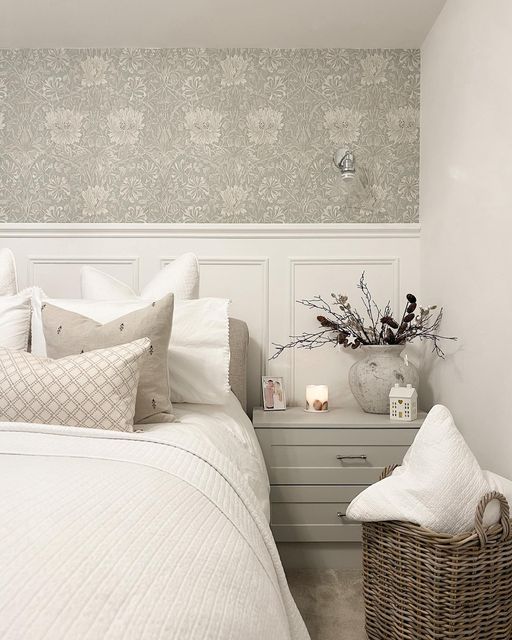 a white bed sitting in a bedroom next to a basket with flowers on top of it