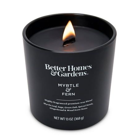 a black candle that is lit up with the words better homes and gardens on it