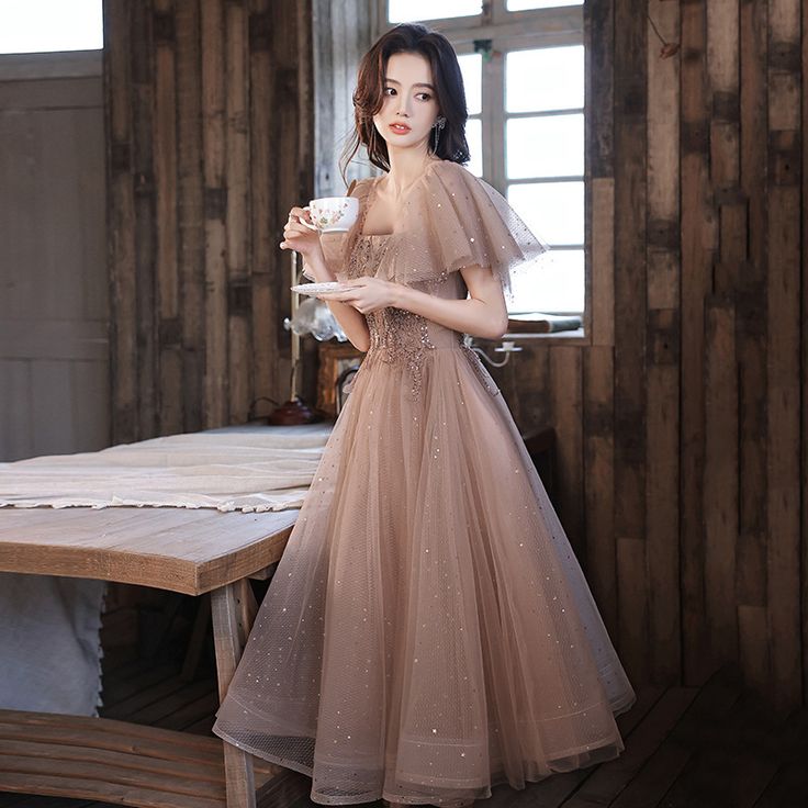 a woman standing in front of a table holding a cup