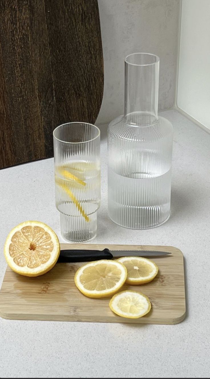 a cutting board with sliced lemons and two glasses