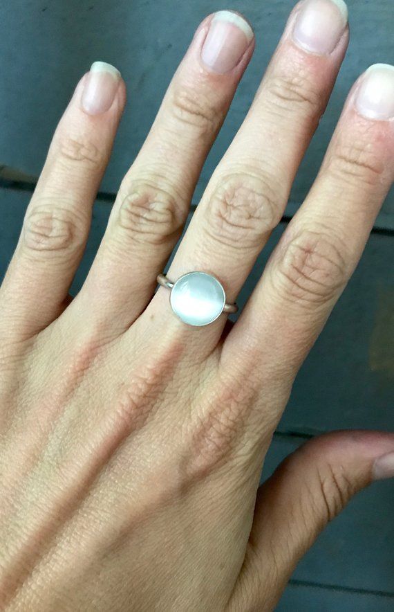 This luminescent white cat's eye stone has been set in sterling silver with a handmade ring band from sterling silver half dome wire. This lovely 12mm round stone catches the light and truly shines. A stunning ring that adds a pop of neutral color to any outfit!Made to order! Choose your gemstone and size! Available in white and blue. Everyday Sterling Silver Cabochon Jewelry, Polished White Moonstone Ring In Sterling Silver, White Polished Moonstone Ring In Sterling Silver, White Moonstone Ring With Polished Sterling Silver, Minimalist Everyday Jewelry With Cabochon, Minimalist Everyday Cabochon Jewelry, Handmade Sterling Silver Moonstone Ring For Everyday, Nickel Free White Round Ring, White Moonstone Ring With Polished Finish For Promise