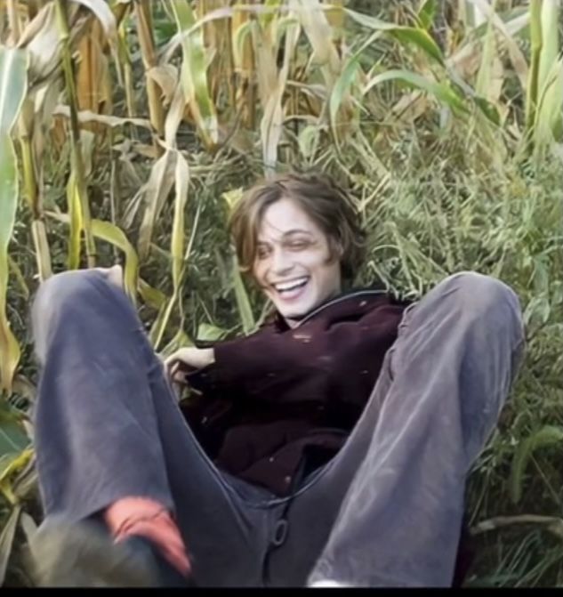 a man sitting in the middle of a corn field with his feet up and mouth open