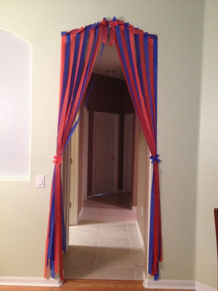 an open door with red and blue curtains on the front entrance to a room that has white walls