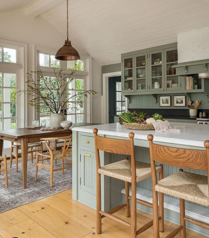 a kitchen with an island and wooden chairs in front of the counter top, along with windows