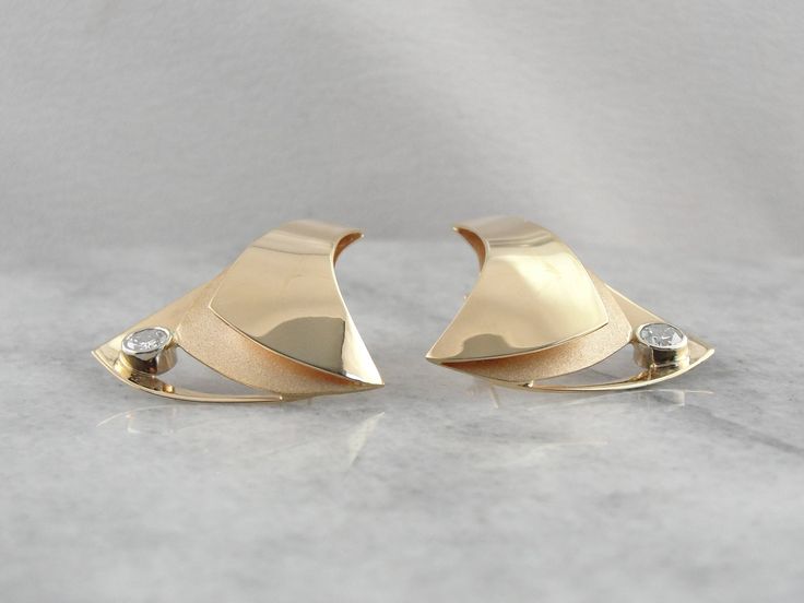 "These bold designer earrings have elegant swaths of polished yellow gold floating over a textured underlayment. A large accent diamond, weighing in at over a quarter carat, adorns the base of these abstract triangular stud earrings, giving this piece another element of sophistication. Metal: 14K Yellow Gold Gem: 2 Diamonds totaling 0.56 Carats, VS in Clarity, G in Color. Earrings Length: 30.5 mm Earring Width: 27.0 mm Marks: \"RH 14K\" Inscribed on the back of the earring SKU #: PHDW0Z-N Each p Polished Yellow Gold Diamond Earrings For Evening, Luxury Diamond Earrings For Anniversary With Polished Finish, Modern Diamond Cut Diamond Earrings For Evening, Modern 14k Gold Earrings With Diamond Accents, Modern Diamond Accent Earrings For Anniversary, Luxury Polished Diamond Earrings For Anniversary, Modern Diamond Earrings With Accents For Evening, Modern Diamond Cut Earrings For Evening, Formal Fine Jewelry Diamond Earrings With Polished Finish