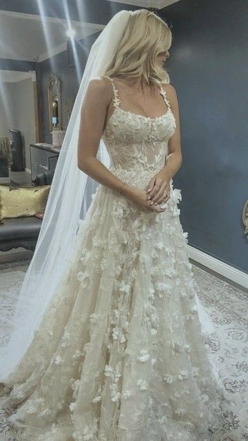 a woman in a wedding dress looking down at her veil and posing for the camera