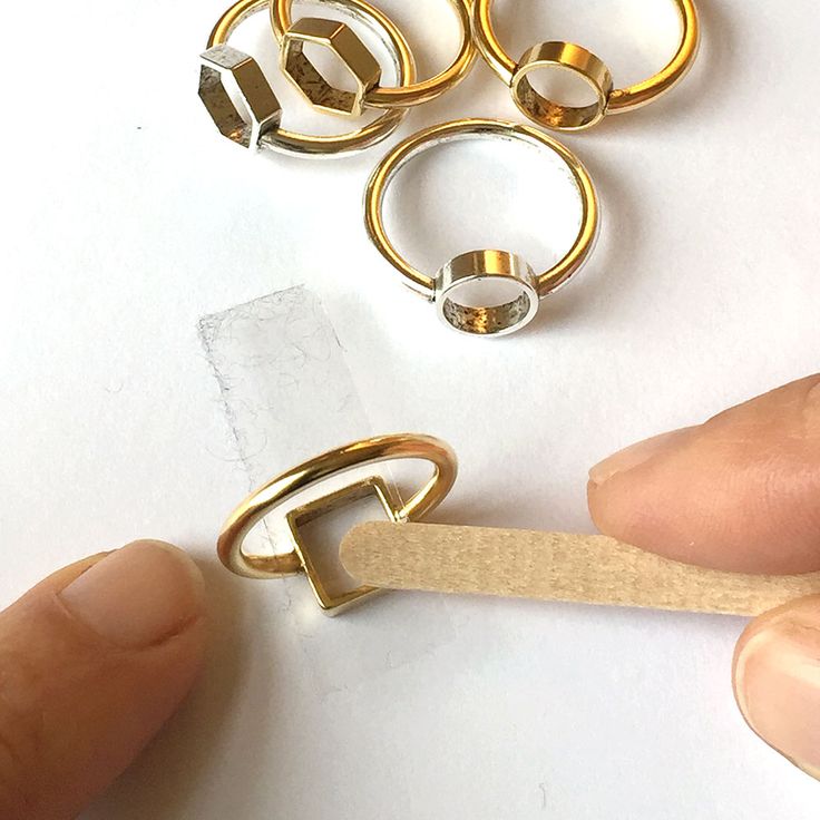 a pair of gold rings being held by a person's finger with a rubber band around them