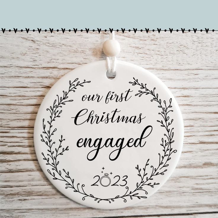 a white ornament with the words our first christmas engaged on it