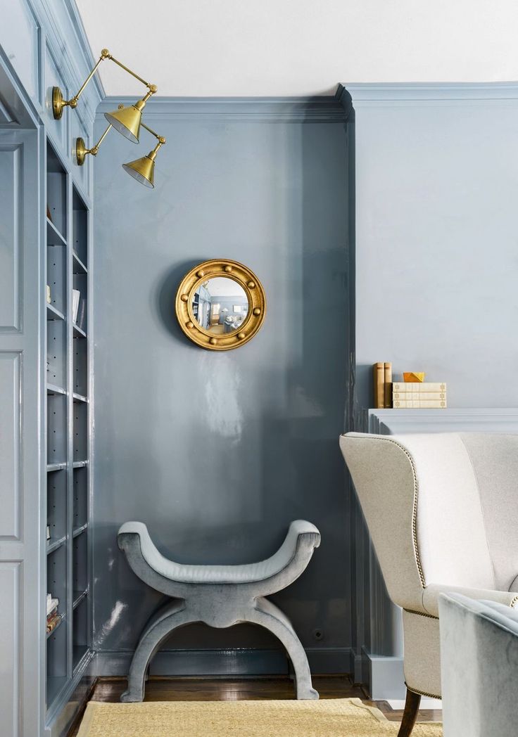 a living room with blue walls and a gold clock on the wall above a bench