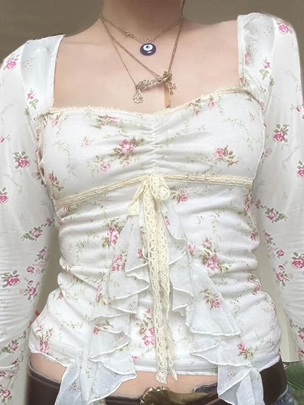 a woman wearing a white top with flowers on it's chest and belt around her waist