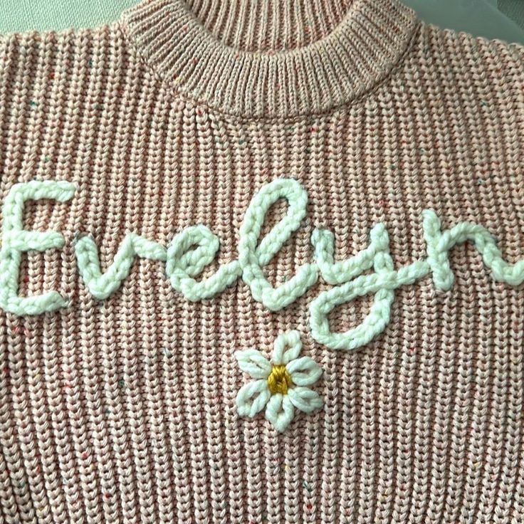 a sweater with the word evelyn written in crochet and a flower on it