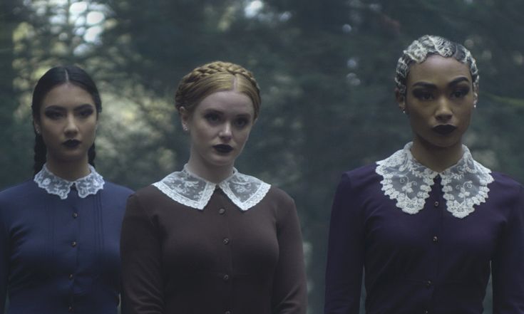 three women with white collars standing in front of trees