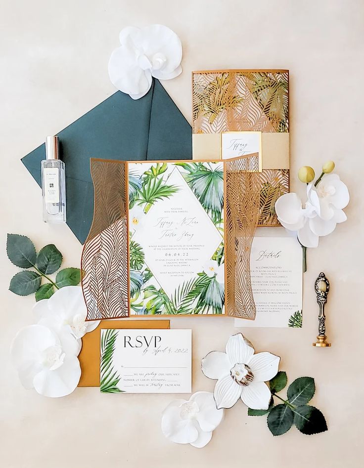 the wedding stationery is laid out on top of each other with flowers and greenery