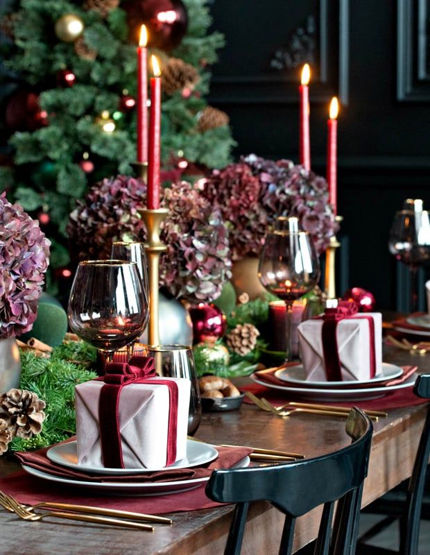 a table set for christmas dinner with candles and napkins