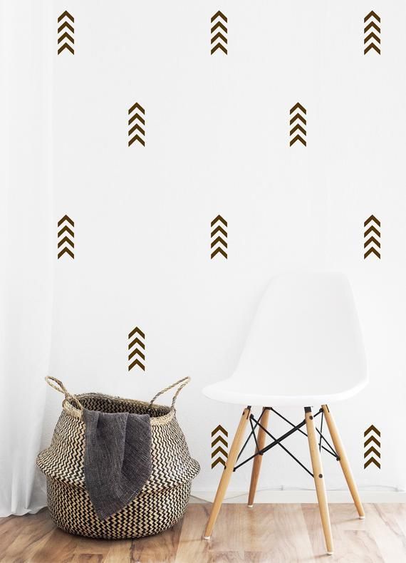 a white chair sitting next to a wall with brown arrows on it and a basket in the foreground