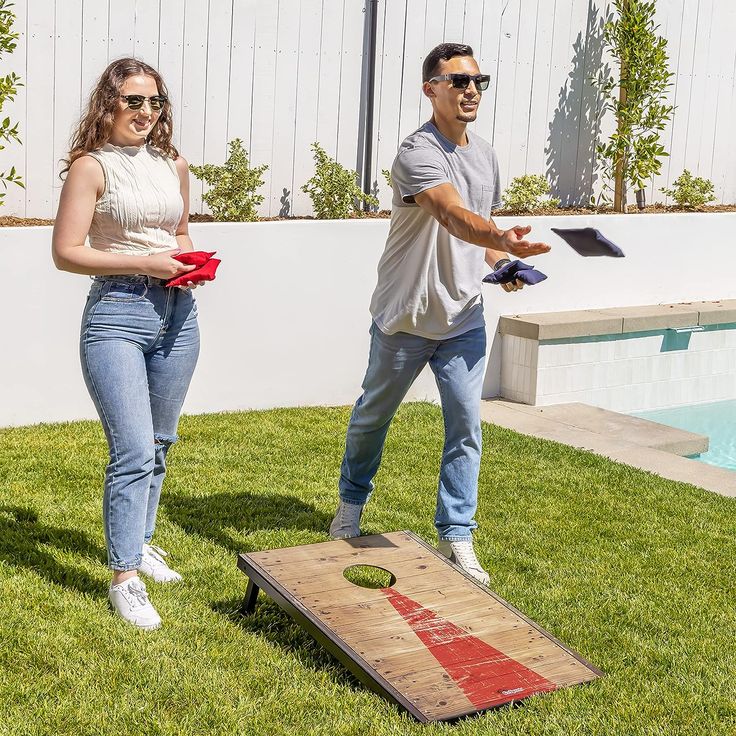 the man and woman are playing cornhole game