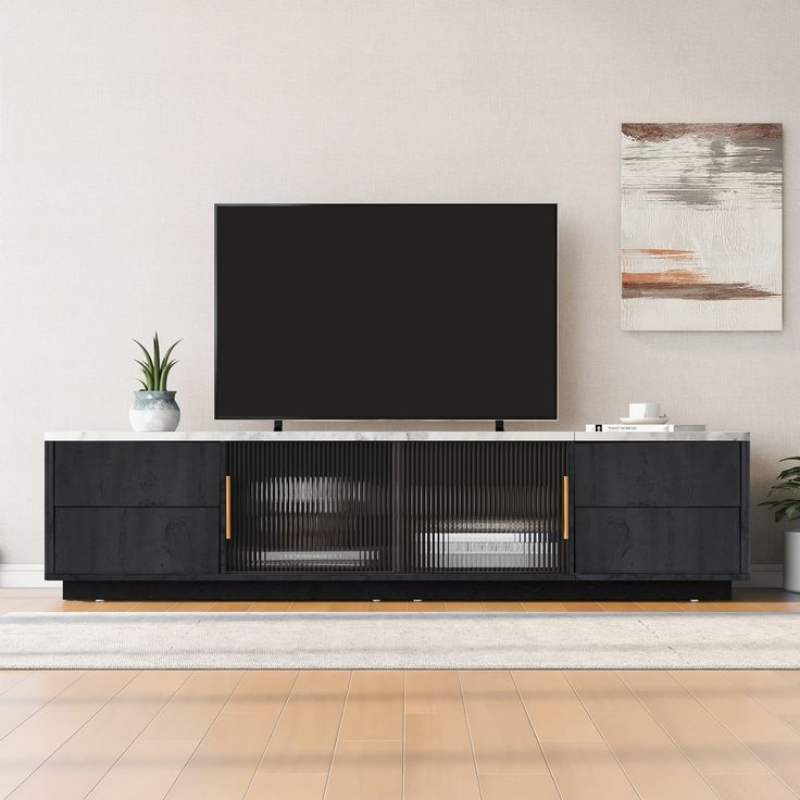 a flat screen tv sitting on top of a wooden entertainment center next to a potted plant