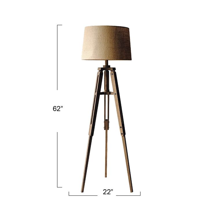 the floor lamp has a wooden tripod base with a beige shade on it, and is