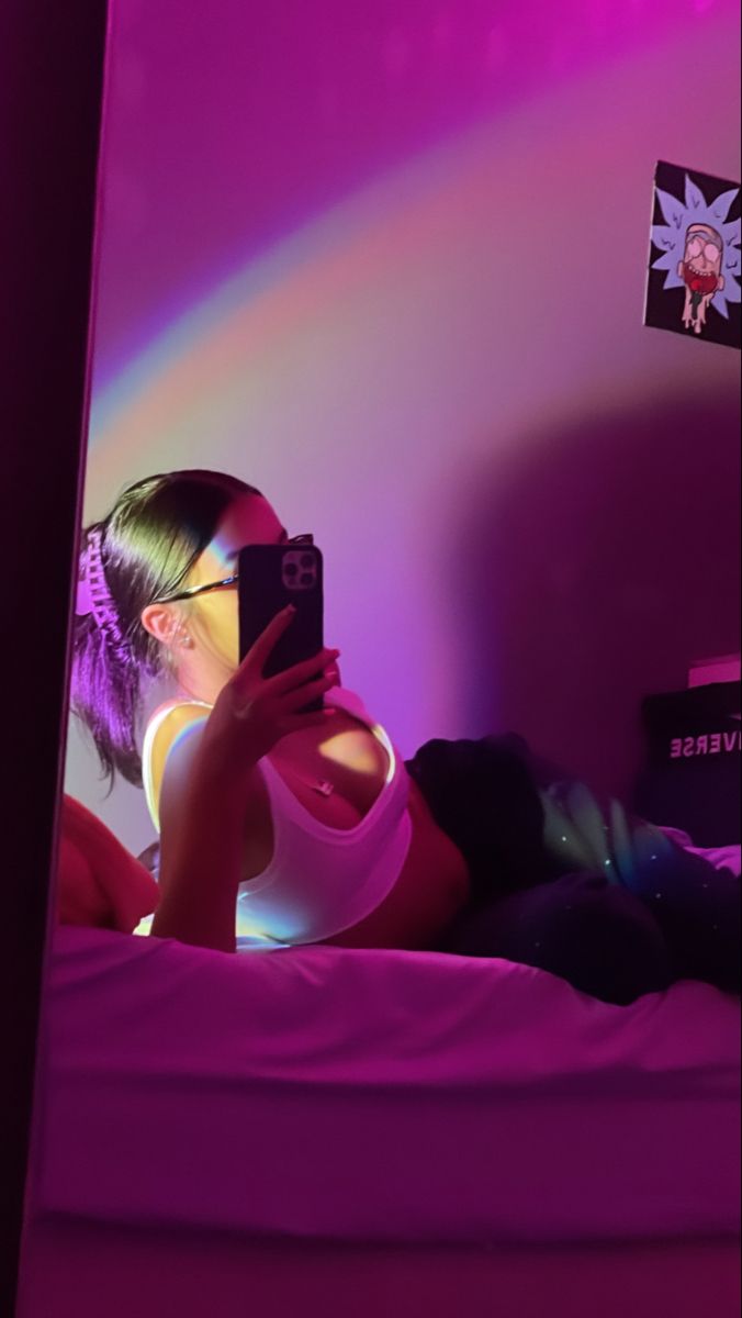 a woman laying in bed taking a selfie with her cell phone while wearing glasses