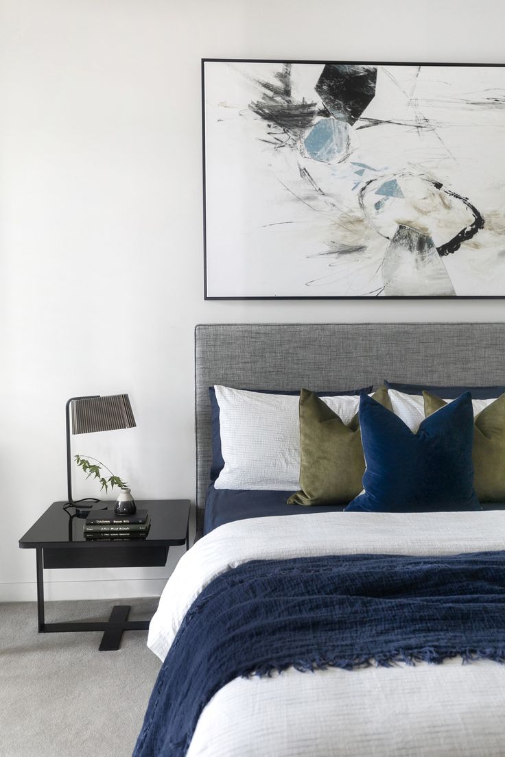 a bed with blue and white pillows on top of it next to a night stand