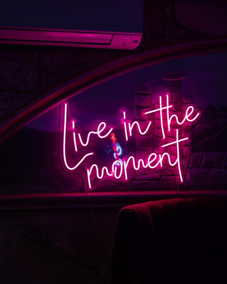 a neon sign that says live in the moment