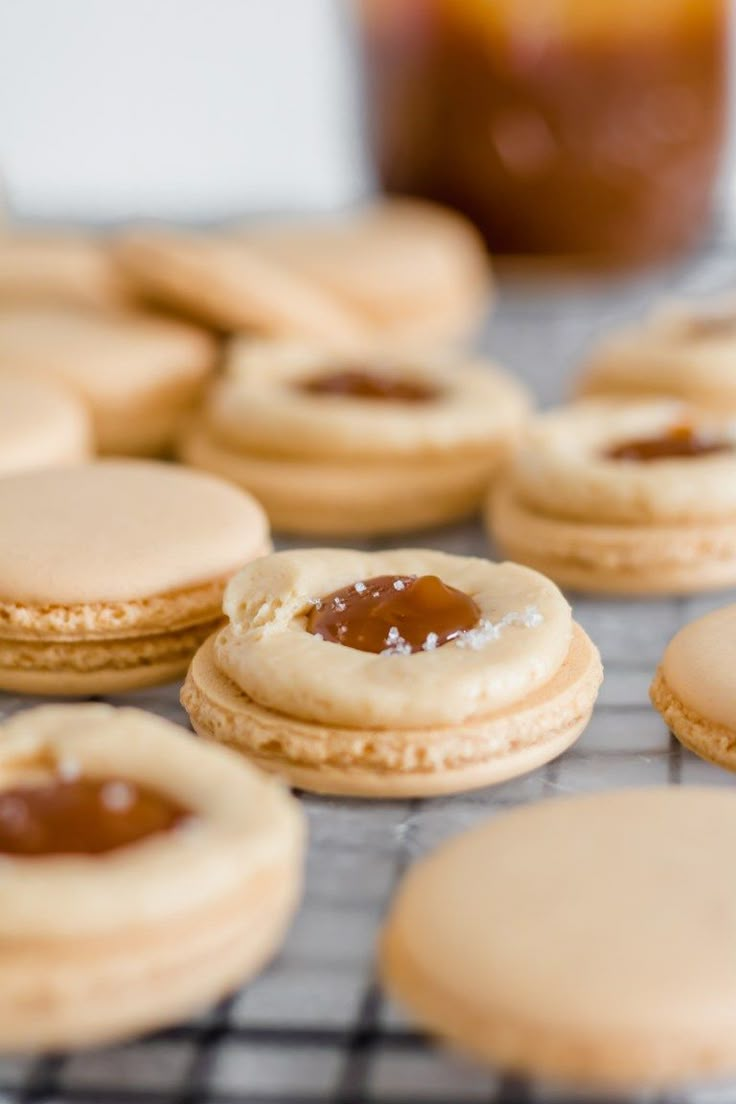 peanut butter and jelly cookies on a cooling rack with jam in the jar behind them