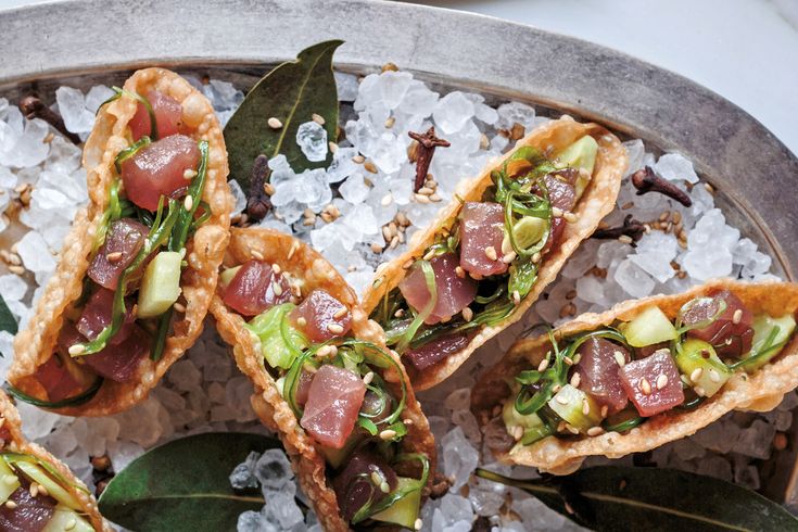 several appetizers are arranged on a platter with ice and leaves around them