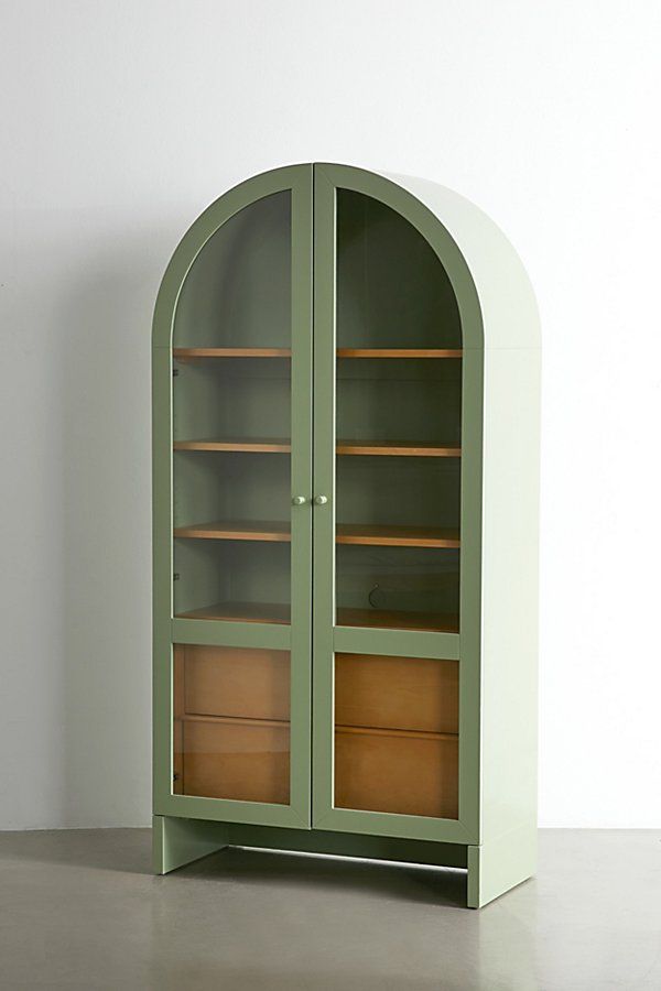 a green bookcase with two wooden drawers in front of a white wall and floor