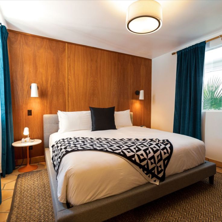 a large bed sitting next to a window in a room with wooden paneled walls