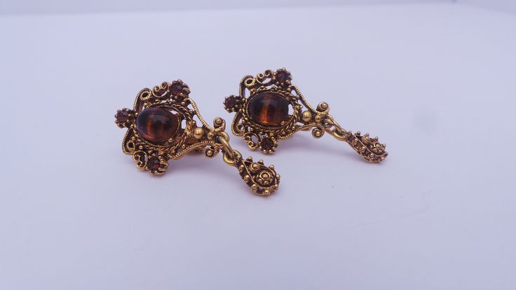 Gorgeous vintage 1950's clip on earrings with a Victorian style. Delicate gold-tone filigree earrings with a teardrop pendant, oval faux tigers eye cameo and citrine colored rhinestone accents. Measures 1 3/8 inches long. Clip on backs, signed Lisner. Shop Policies: Shipping: All items will be shipped through the USPS unless otherwise marked. Most items will be shipped first class. Expect shipment within 1-2 business days from date of payment. Refunds:Vintage items are all used and have varying Victorian Style Metal Clip-on Jewelry, Vintage Gold Teardrop Plug Earrings, Vintage Teardrop Pierced Earrings, Ornate Antique Gold Earrings For Formal Occasions, Vintage Teardrop Clip-on Earrings As Gift, Vintage Brass Clip-on Earrings, Ornate Clip-on Drop Earrings, Antique Metal Earrings With Vintage Charm, Vintage Brass Drop Clip-on Earrings