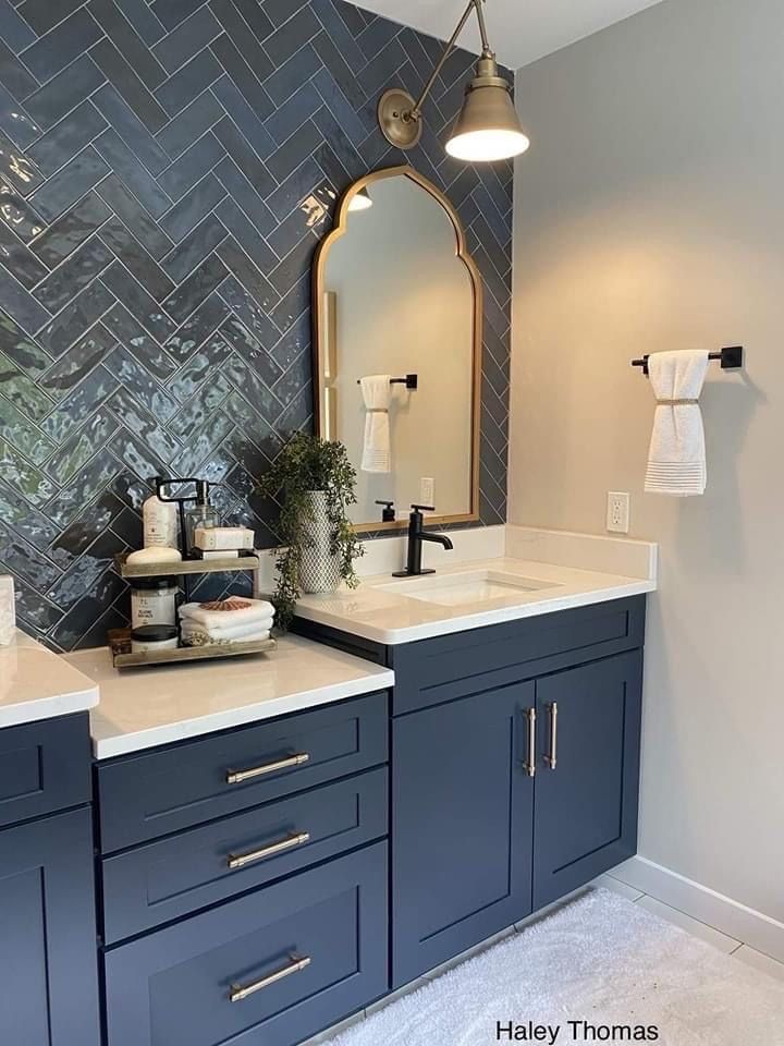 a bathroom with two sinks and a large mirror on the wall above it is decorated in gray herringbone tile