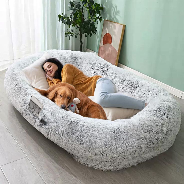 a woman laying on top of a dog bed