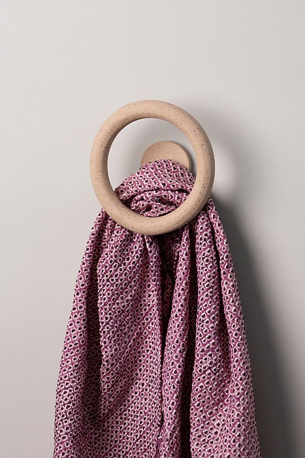 a pink scarf with a wooden ring hanging from it's end on a wall