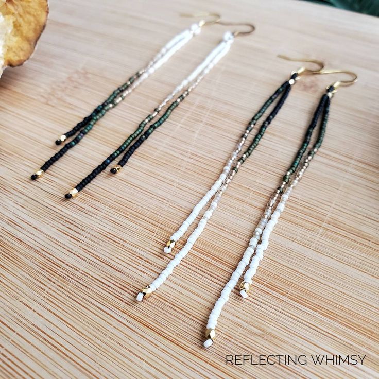 three pairs of beaded earrings sitting on top of a wooden table next to a piece of bread