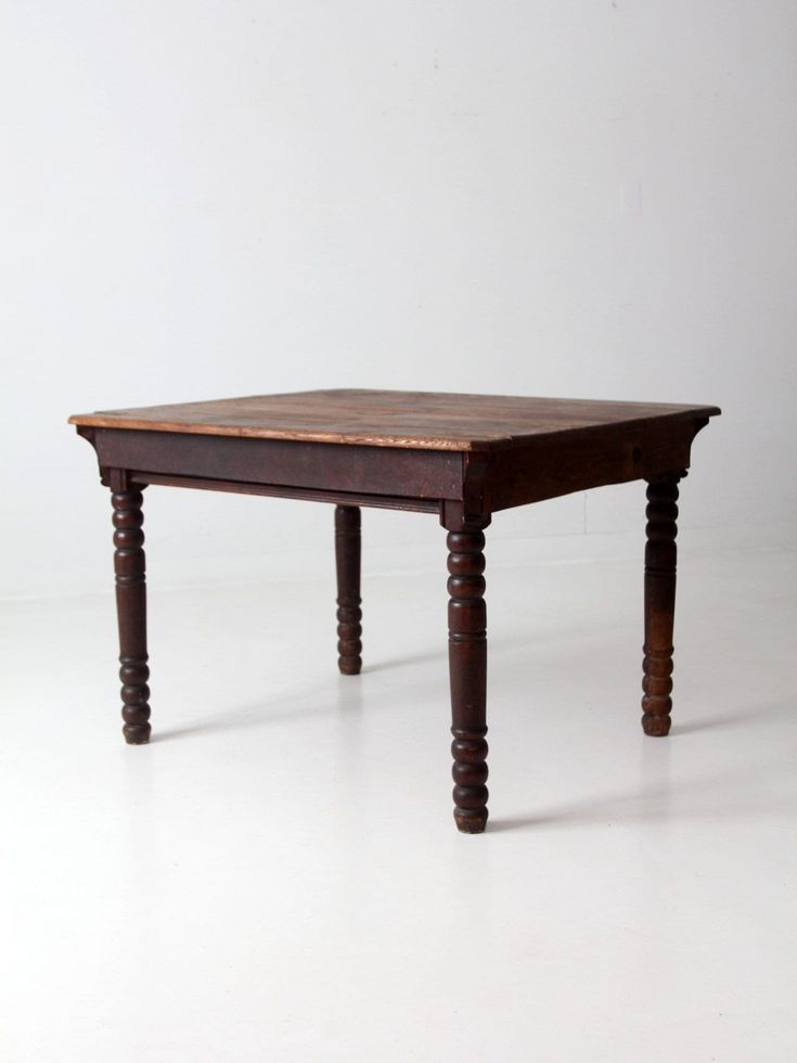 an old wooden table sitting on top of a white floor with no one around it