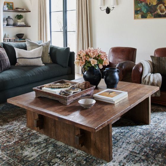 a living room filled with furniture and a coffee table in front of a large window