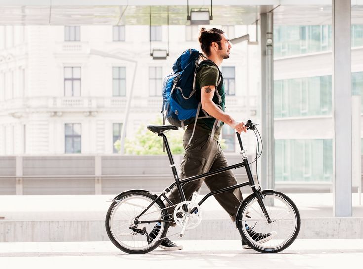 a man with a backpack is walking his bike