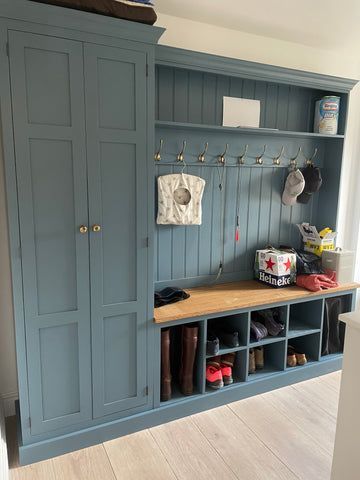 a mud room with blue cabinets and shoes