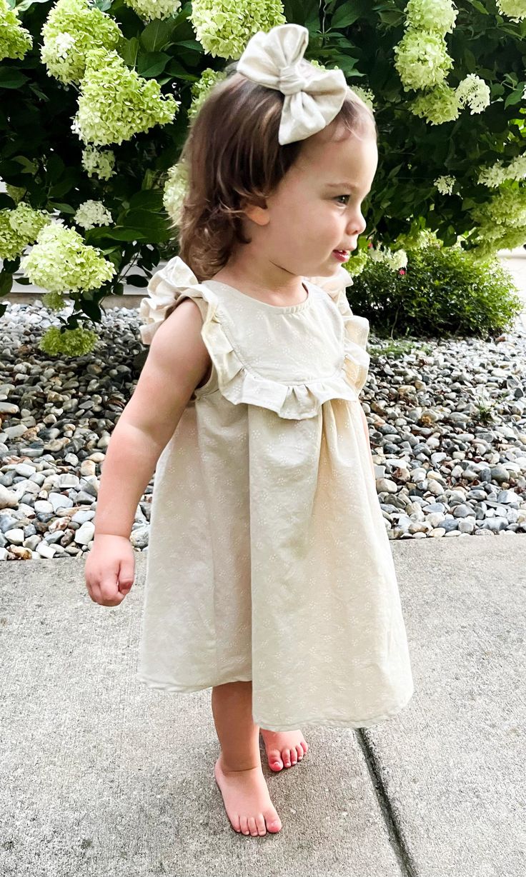 Sizes: 0-3 Month to 8 Years Skill level: IntermediateFormats: A4/Letter, A0, ProjectorFabric: lightweight woven Olena is a sleeveless dress with ruffles at the front extending over shoulders to back, a full button opening at the back, and a gathered seam above a flared skirt. The bodice is unlined with arm and neck openings finished with a single-fold bias tape. Designed to have a regular fit with moderate ease around the chest. Length falls an inch below the knee, the bottom hem is slightly rou Sleeveless Ruffle Hem Dress For Dress-up, Cute Summer Dresses For Dress-up Occasions, Beach Dresses With Ruffled Straps, Spring Dress-up Dresses With Ruffle Sleeves, Summer Ruffle Sleeve Dress For Casual Occasions, Spring Dresses With Ruffled Straps, Summer Cotton Mini Dress With Ruffles, Cute Mini Dress With Ruffled Straps And Ruffles, Cute Mini Dress With Ruffled Straps